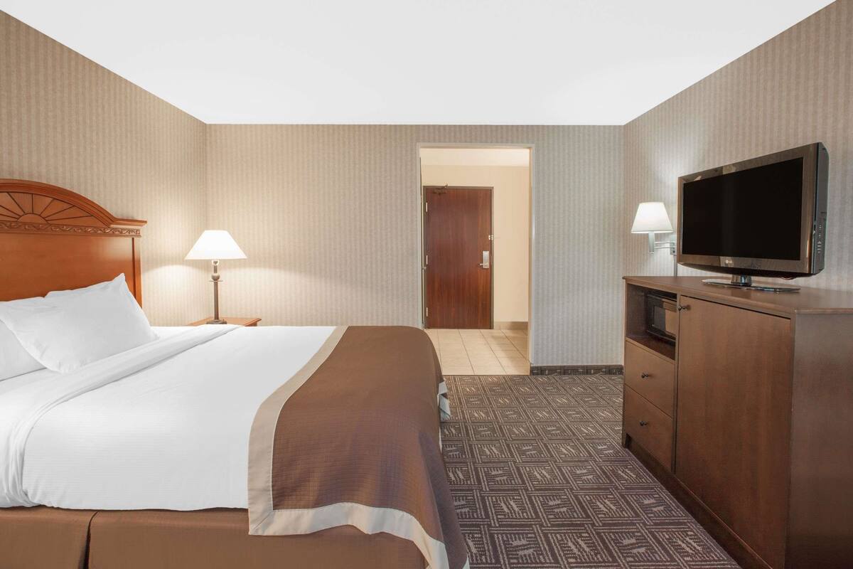 A hotel room with a bed, a television, a desk, and a lamp.