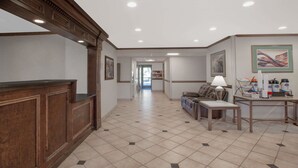 A spacious lobby with a reception desk, a sofa, a coffee table, and a lamp. - Baymont by Wyndham Jackson (Jackson)