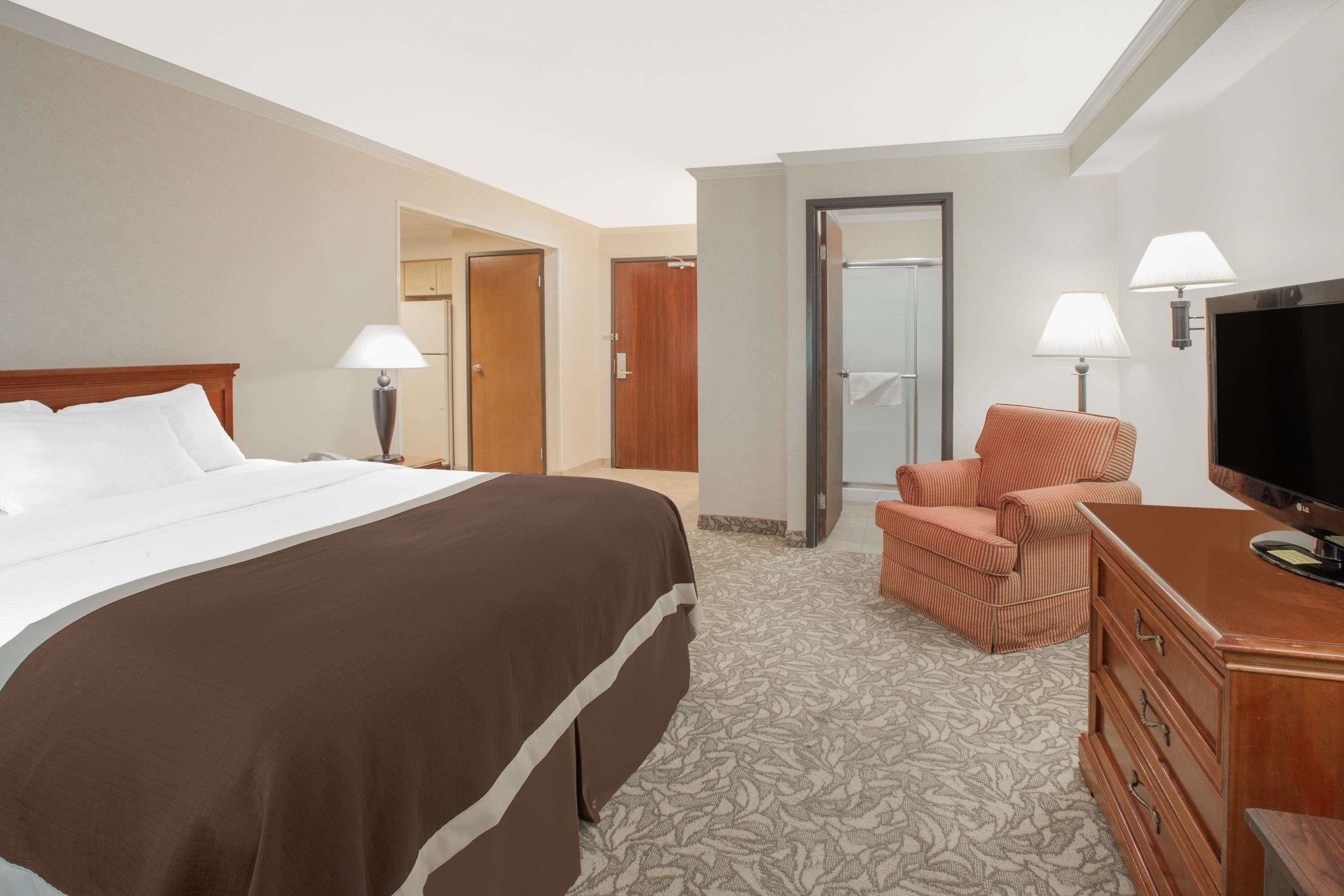 Une chambre d’hôtel avec un grand lit, une télévision, une chaise et une commode.