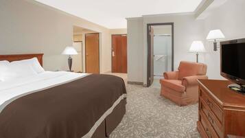 A hotel room with a large bed, a television, a chair, and a dresser.