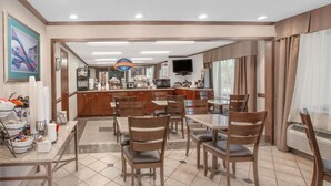 A hotel dining area with a central island, multiple tables, and chairs. - Baymont by Wyndham Jackson (Jackson)