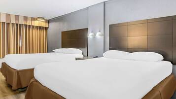 A hotel room with two beds, a large mirror, and a curtain.