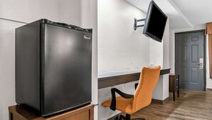 Een compacte kitchenette met een zwarte koelkast, een houten kastje en een aan de muur bevestigde televisie.