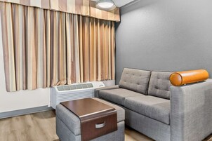 Una sala de estar moderna con un sofá gris, una mesita de madera y un equipo de aire acondicionado blanco.