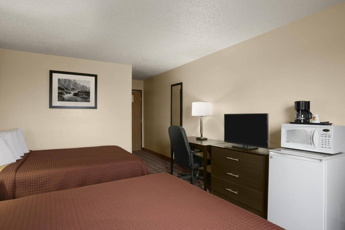 Habitación de hotel con dos camas, un escritorio con computadora, un microondas y una cafetera.