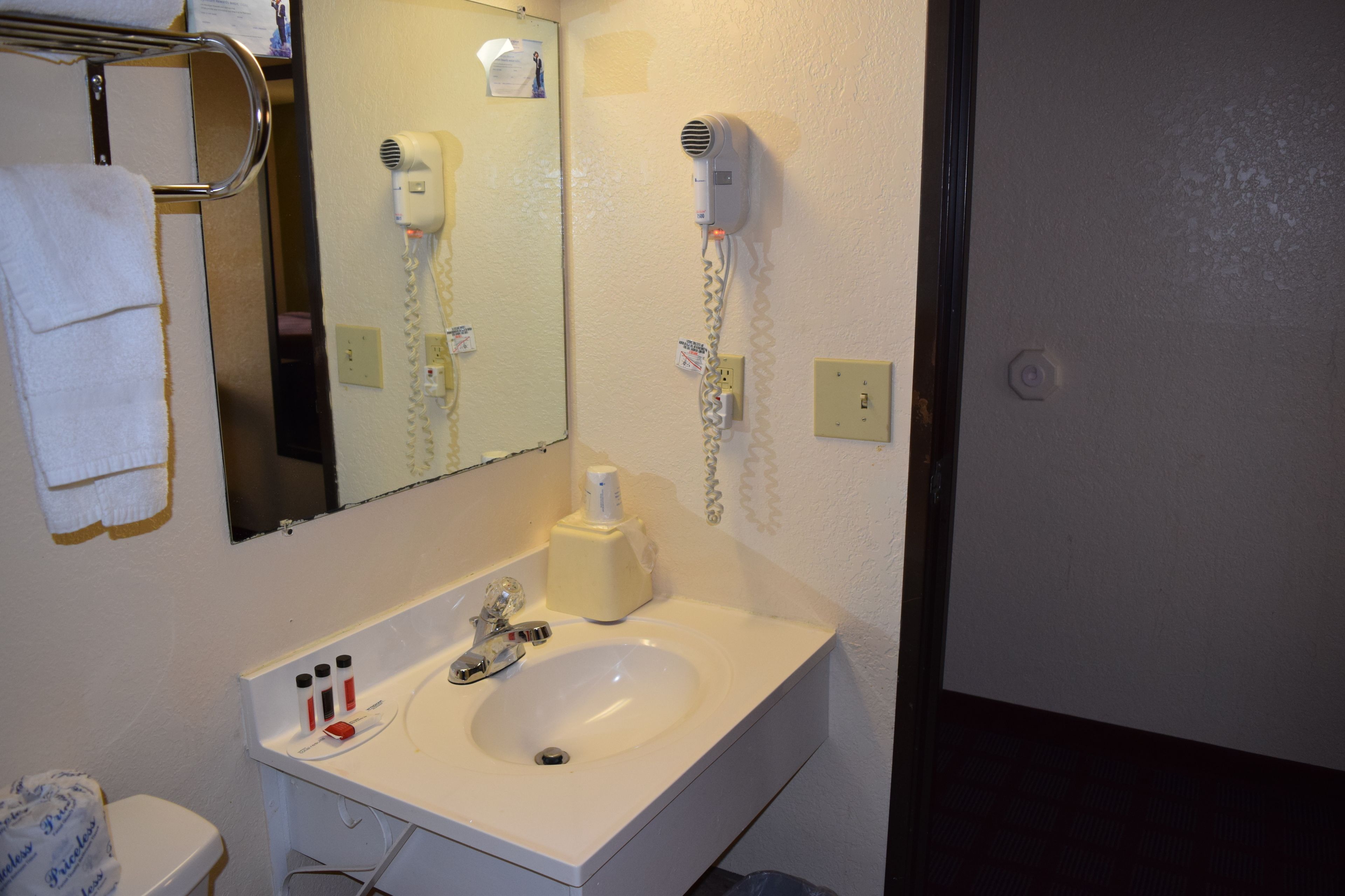 Een badkamer met een wastafel, spiegel, handdoekhouder, haardroger en toiletartikelen.