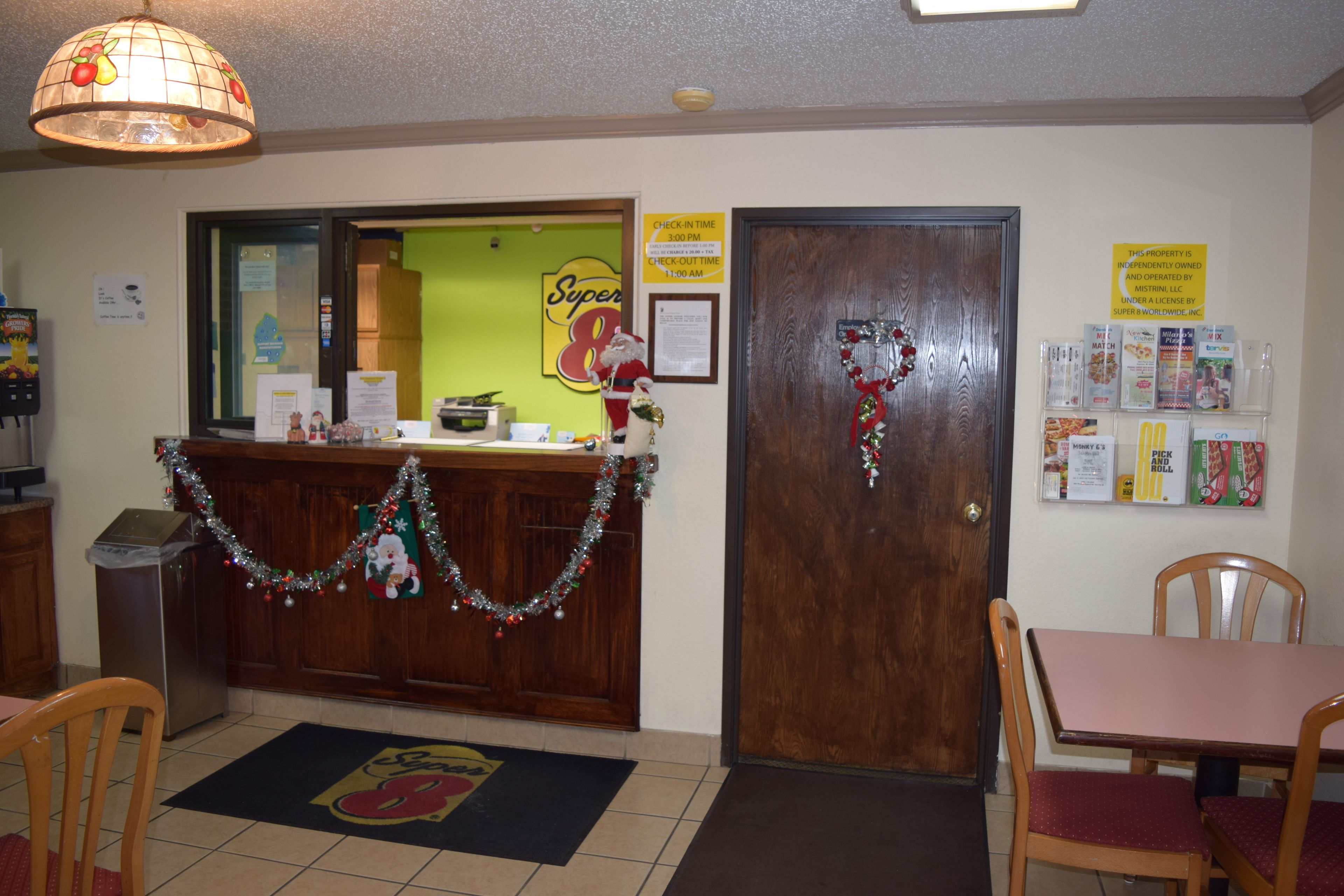 A restaurant interior with a wooden counter, festive decorations, a check-in/out sign, and a menu board.
