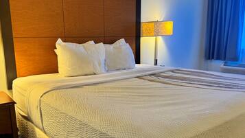 Een hotelkamer met een groot bed, een houten hoofdbord, een bedlampje en een raam met gordijnen.