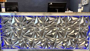 Un comptoir d’accueil avec un mur arrière orné d’un motif géométrique et le logo « Baymont » sur le tapis.