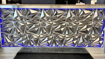 A reception desk with a geometric patterned back wall and a 'Baymont' logo on the carpet.