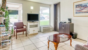 A living room with a television, a coffee machine, and a bookshelf. - OYO Hotel Jackson North I-55 (Jackson)