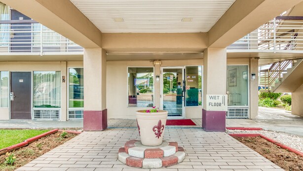 A hotel entrance with a wet floor sign, a potted plant, and a staircase. - OYO Hotel Jackson North I-55 (Jackson)
