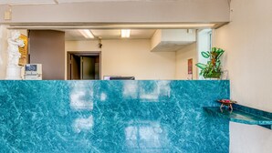 A reception area with a blue marble counter, a statue, a clock, and a plant. - OYO Hotel Jackson North I-55 (Jackson)