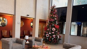 A spacious lobby with two grey sofas, a Christmas tree, and a large window offering a view of the outside. - Mariposa Hotel (Nogales)