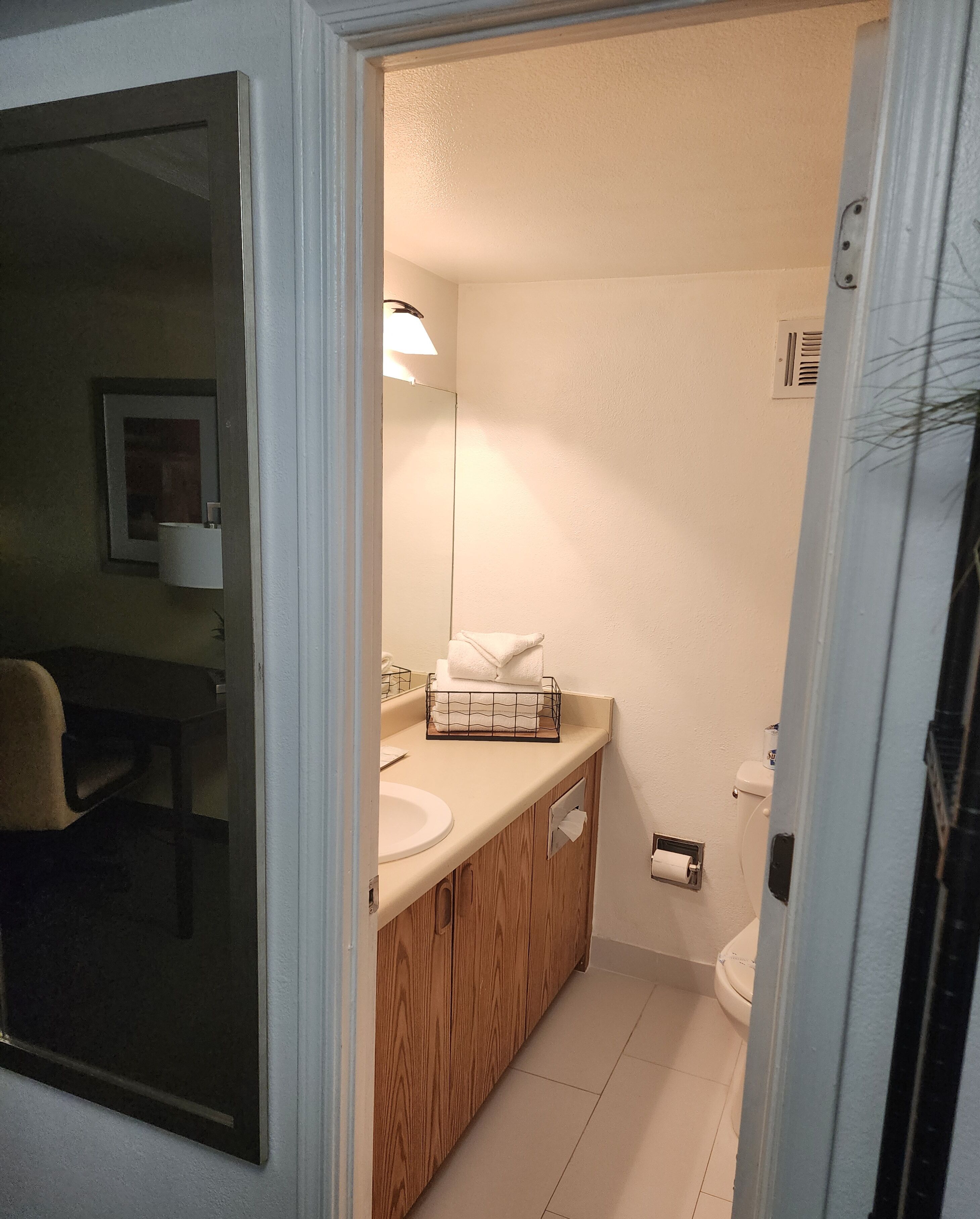 A bathroom with a wooden vanity, a toilet, and a sink.