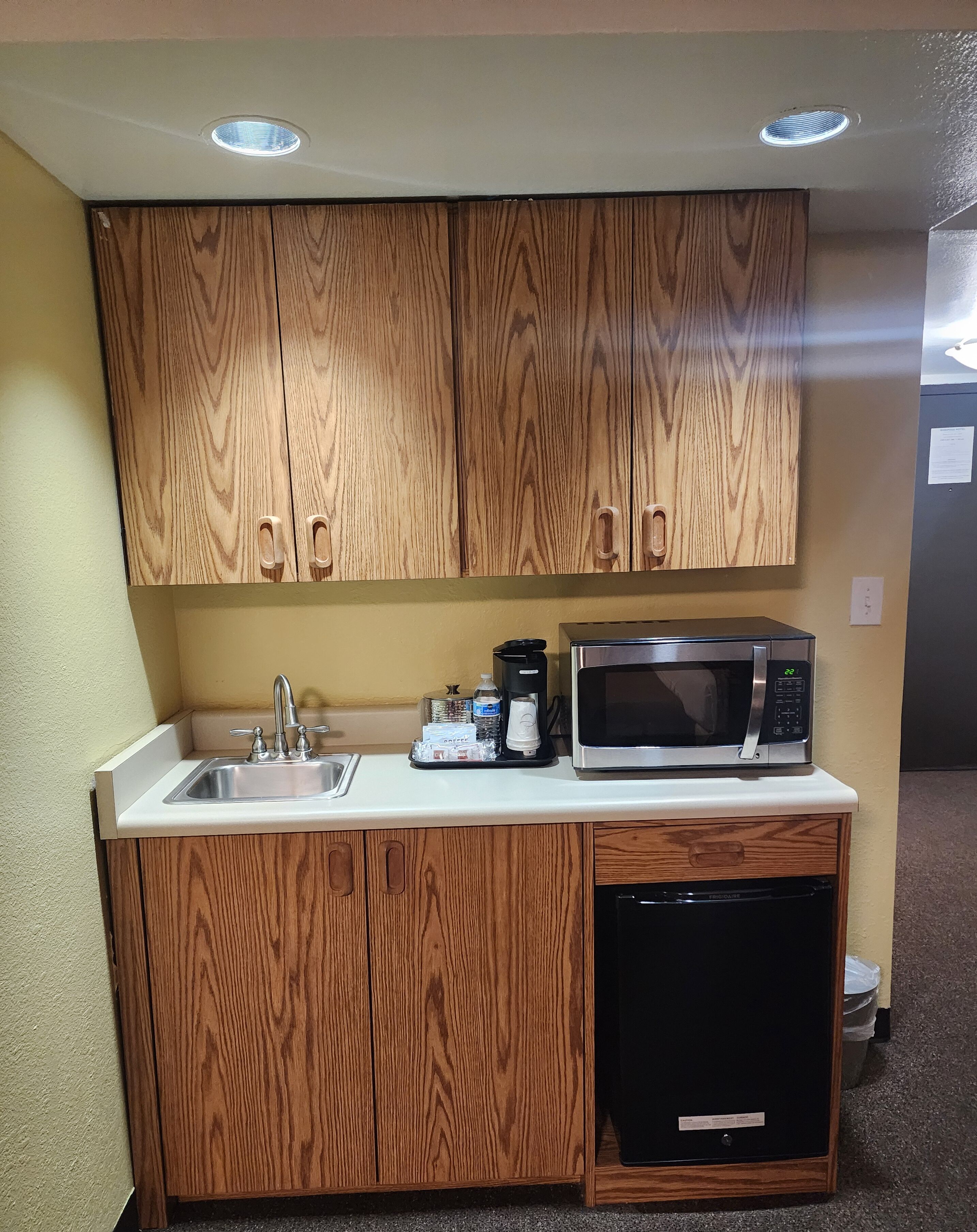 A compact kitchen with wooden cabinets, a sink, a microwave, and a dishwasher.