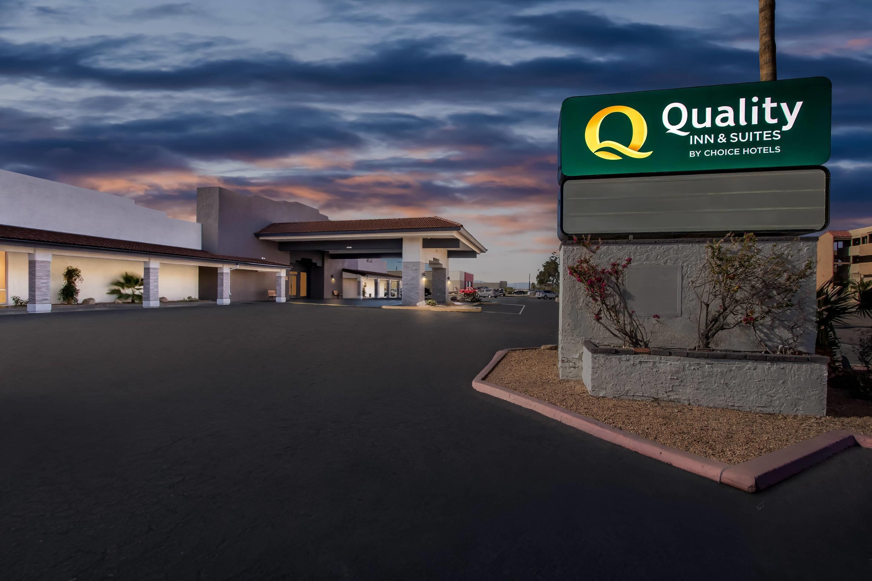 Ein Hotel Eingang mit einem Schild, das "Quality Inn & Suites by Choice Hotels" zeigt, und einer Tankstelle im Hintergrund.