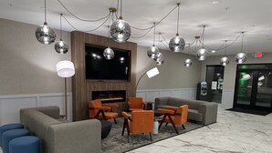 A lobby with a fireplace, sofas, and a TV.