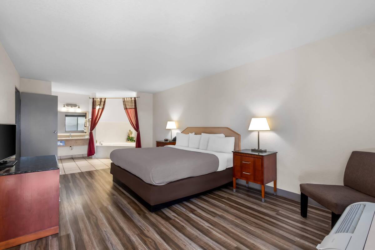 A hotel room with a bed, bedside tables, a desk, and a chair.