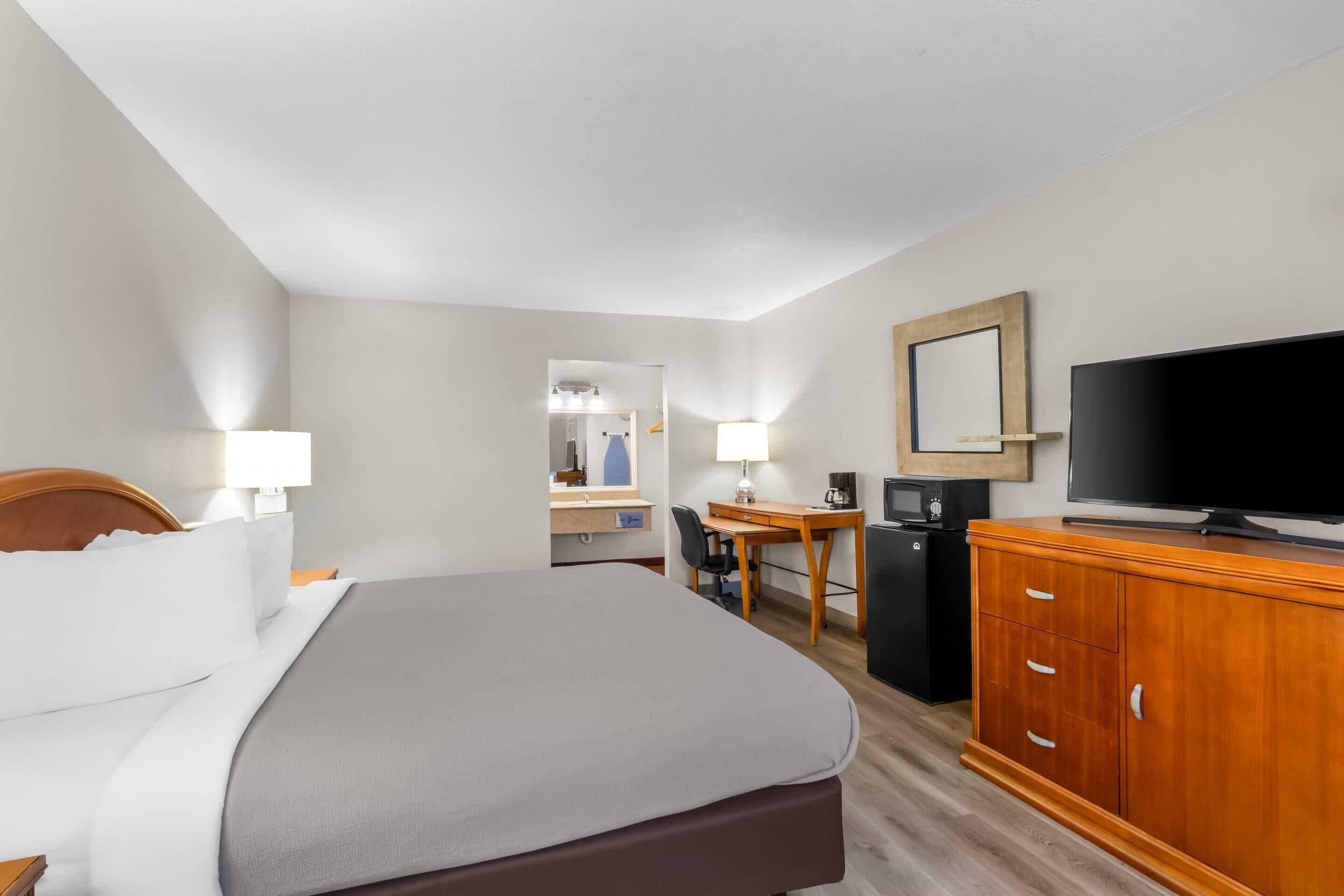 A hotel room with a bed, a desk, a television, and a cabinet.