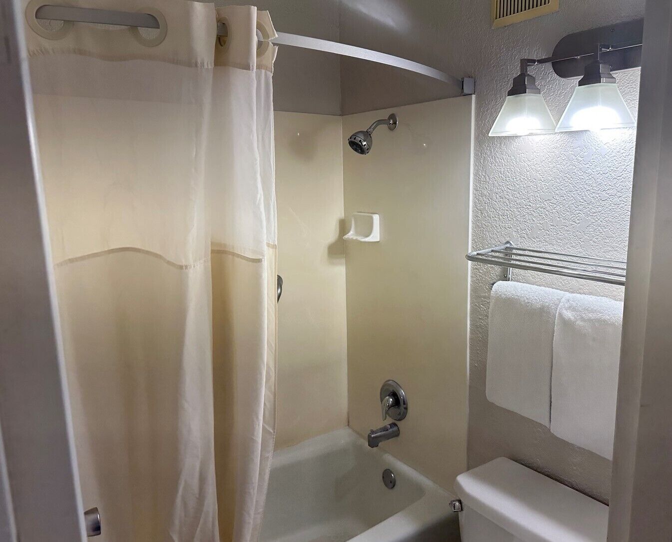 A bathroom with a bathtub, a shower curtain, a towel rack, and a mirror.