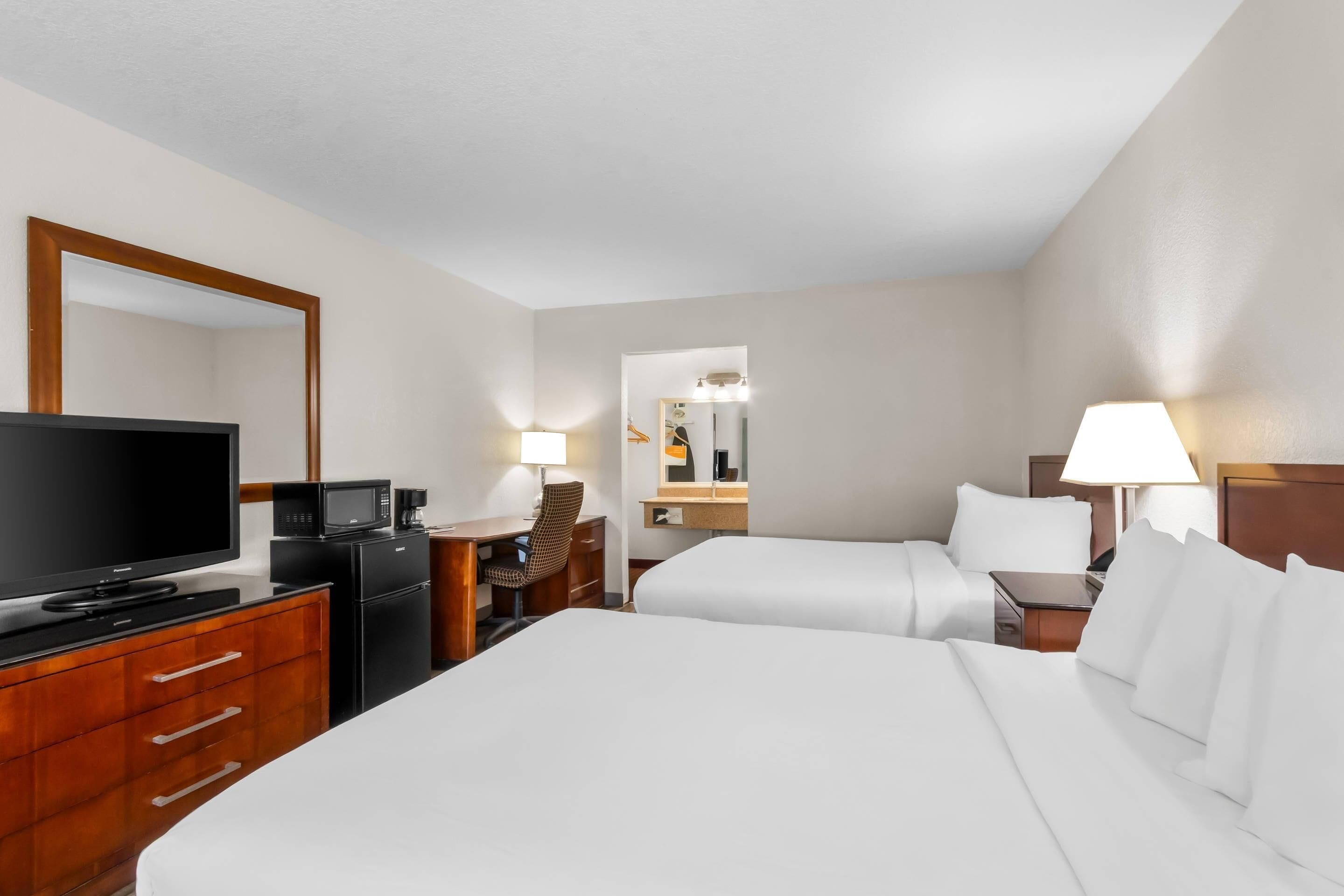 Habitación de hotel con una cama grande, un escritorio con ordenador, televisor y microondas.
