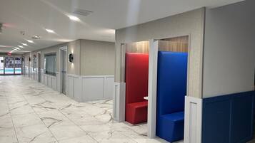 A hallway with marble flooring, red and blue seating areas, and a pool entrance.