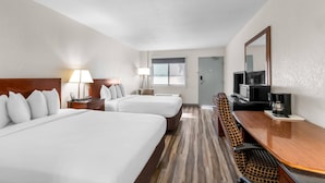 A hotel room with two beds, a desk with a TV, a coffee maker, and a window.