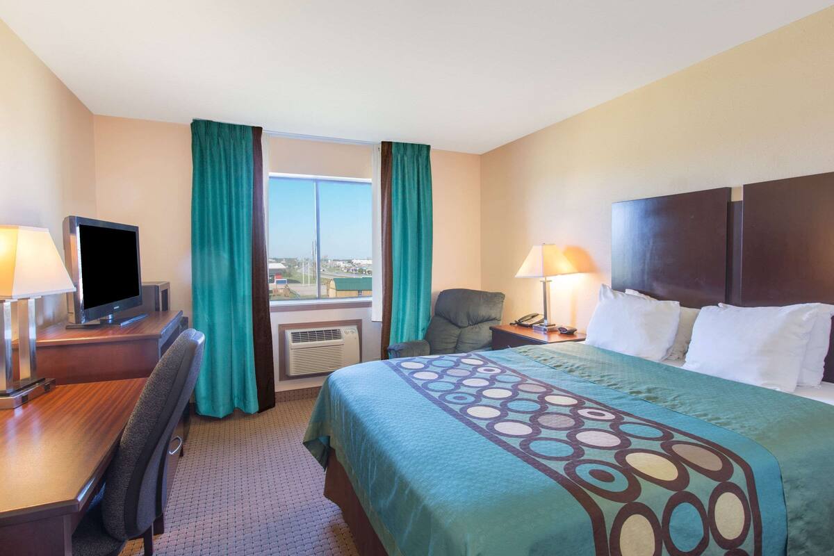 Ein Hotelzimmer mit Bett, Schreibtisch, Stuhl, Fernseher und Blick auf die Stadt.