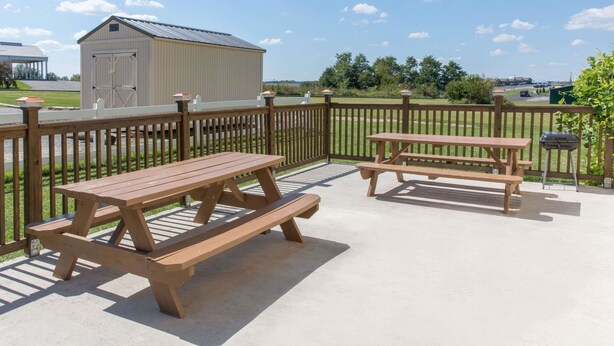 An outdoor patio with picnic tables and a wooden fence.