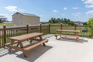Une terrasse extérieure avec des tables de pique-nique et une clôture en bois.