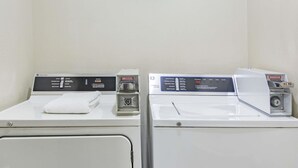 Two front-loading washing machines in a laundry room with a white towel on the left machine.
