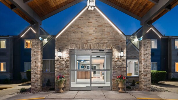 A building with a stone facade, a large glass entrance, and a covered area with wooden beams. - Microtel Inn by Wyndham Lexington (Lexington)