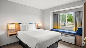 A hotel room with a bed, bedside tables, a window with curtains, and a view of the outside. - Microtel Inn by Wyndham Lexington (Lexington)