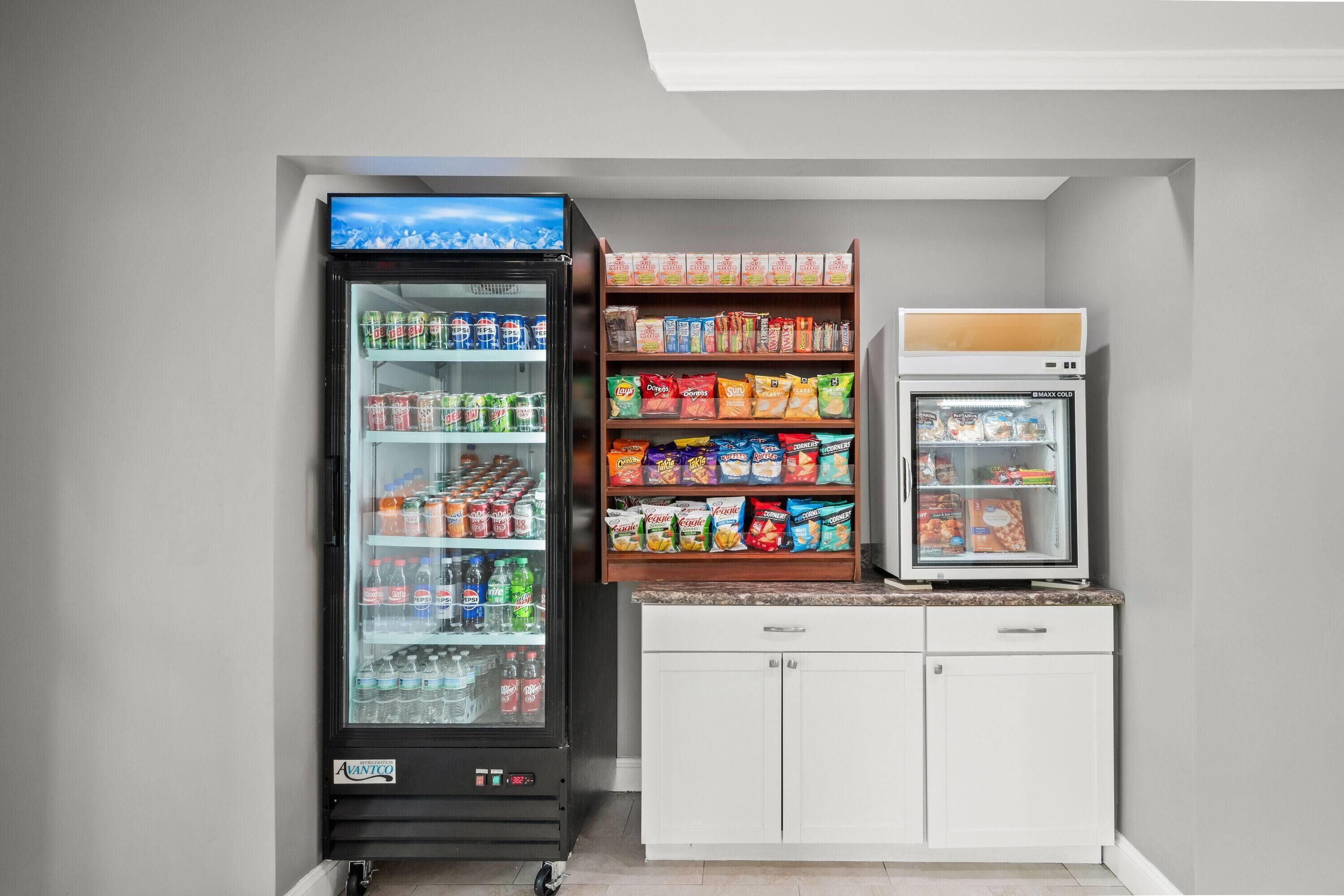 Un distributeur automatique proposant une variété de collations et de boissons, un réfrigérateur et un petit congélateur.
