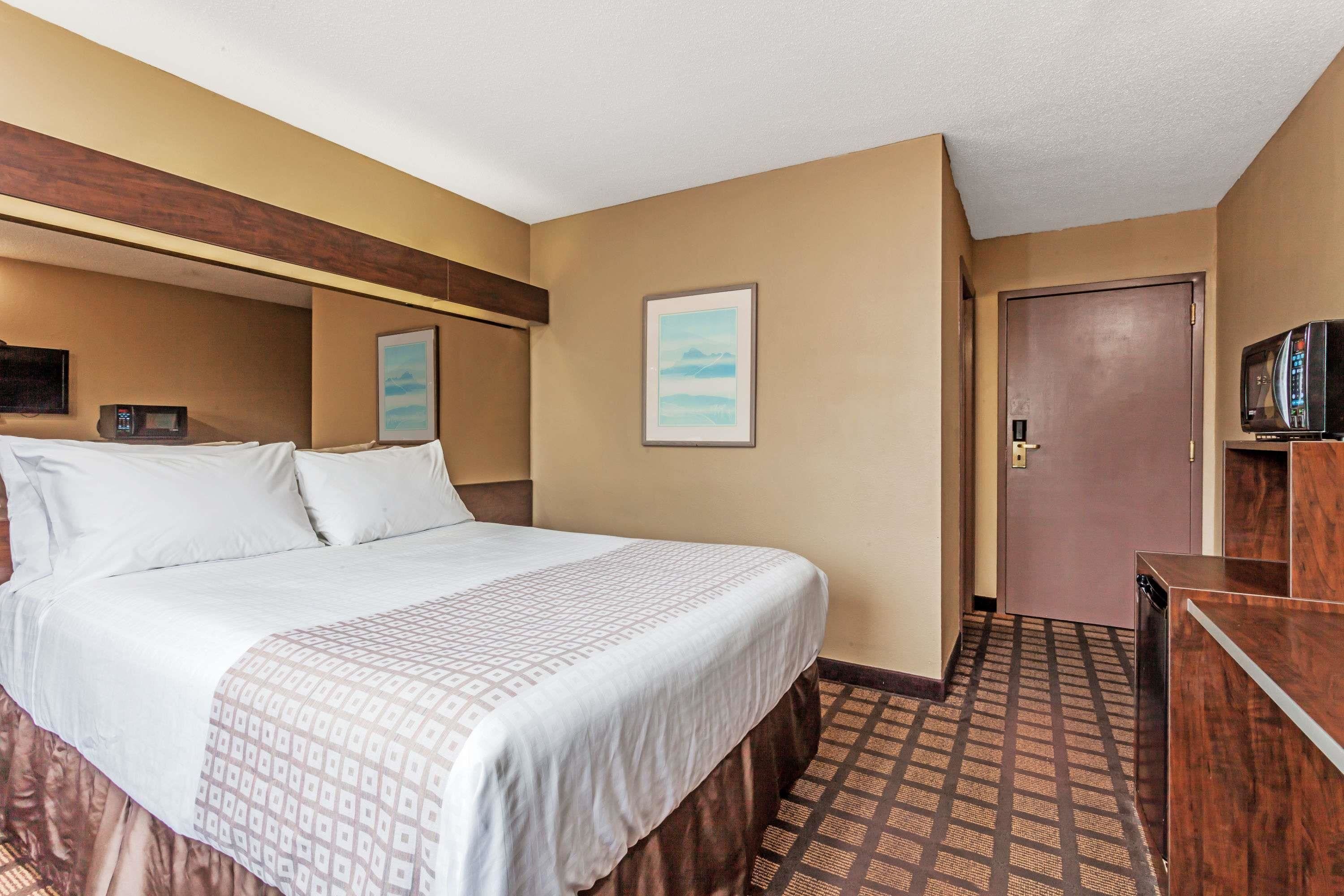 Ein Hotelzimmer mit Bett, Fernseher, Mikrowelle und einer Tür zu einem anderen Raum.