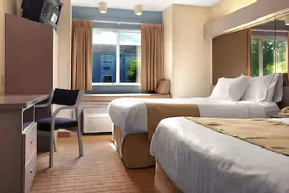 A hotel room with a bed, a desk, a chair, a television, and a window with curtains.