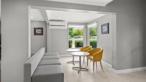 A modern waiting area with a bench, two tables, and chairs. - Microtel Inn by Wyndham Lexington (Lexington)