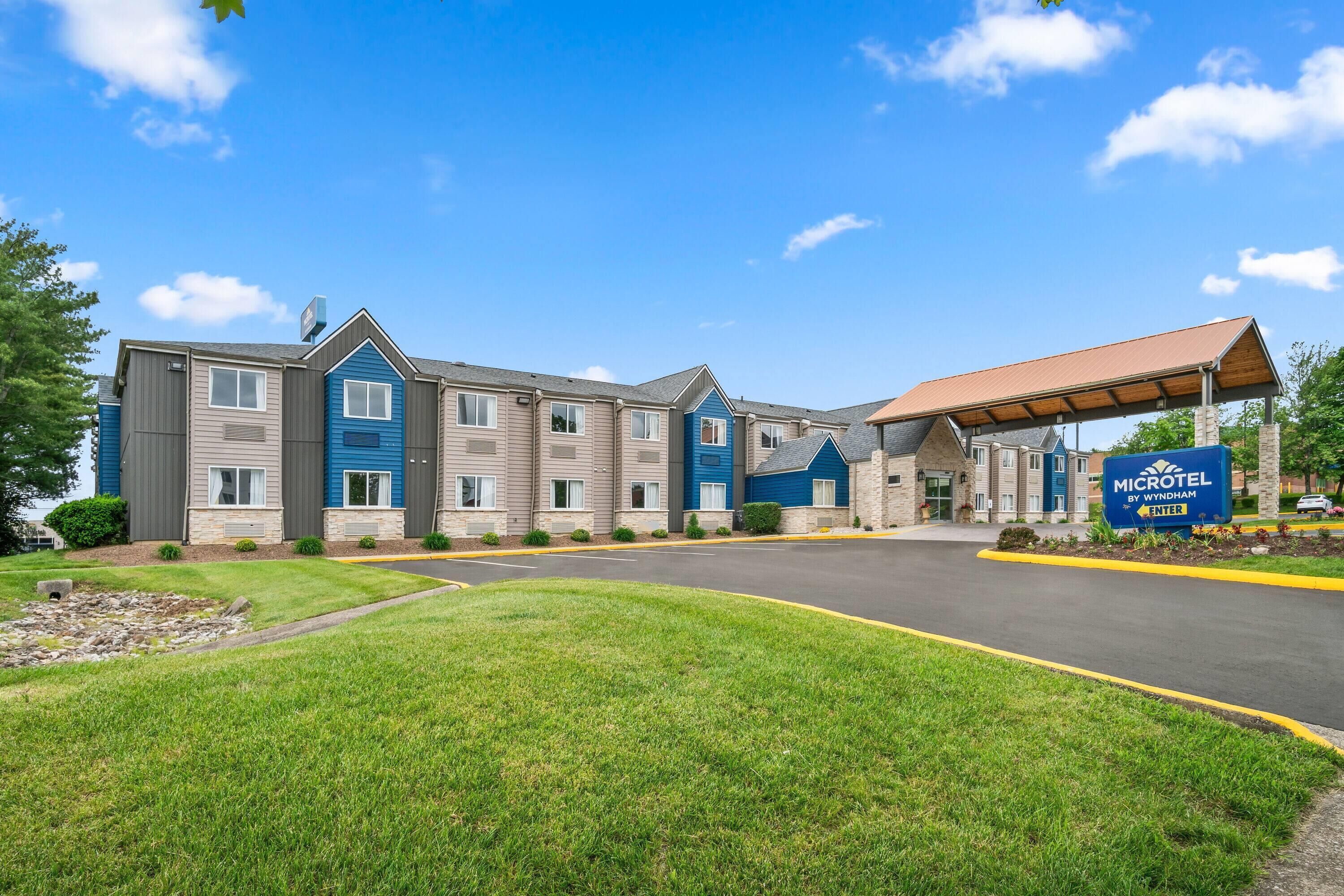 A Microtel by Wyndham hotel with a covered parking area and a well-maintained lawn.
