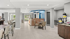 A modern hotel lobby with a reception desk, seating area, and a kitchenette. - Microtel Inn by Wyndham Lexington (Lexington)