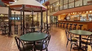 A spacious indoor area with multiple tables and chairs, a central bar area, and a high ceiling with decorative elements. - Ramada Hotel & Conference Center by Wyndham Paintsville (Paintsville)