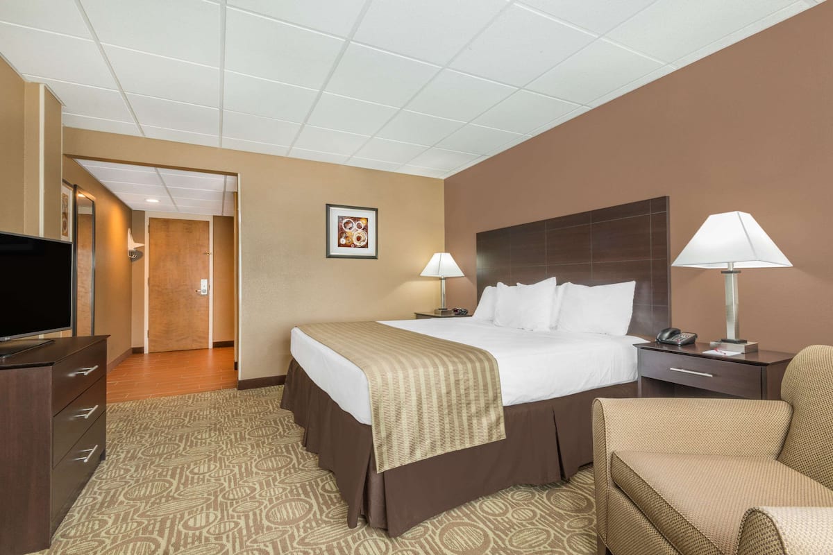 A hotel room with a bed, bedside lamps, a TV, a desk, and a chair.