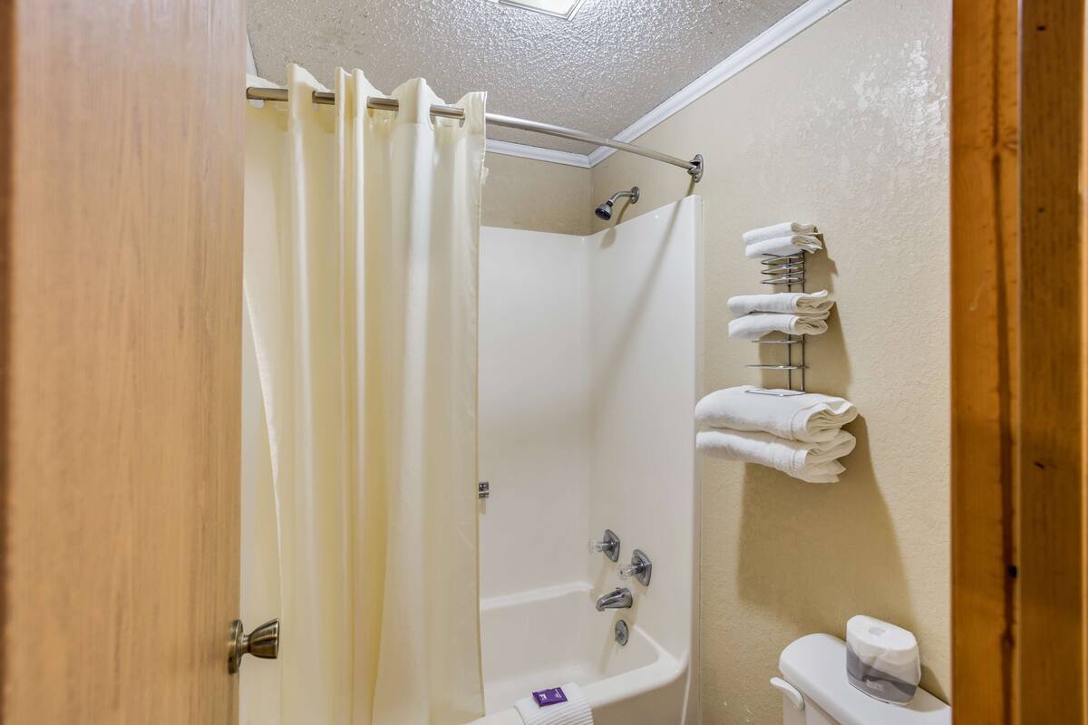 A bathroom with a shower, a sink, and a toilet. There are towels hanging on a rack.