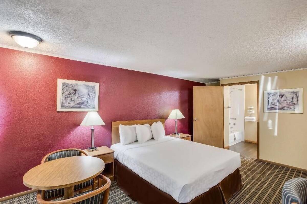 A hotel room with a bed, bedside tables, a chair, and a small table.