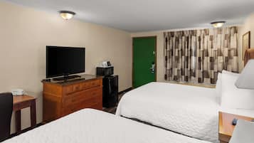 A hotel room with two beds, a television, a dresser, and a green door.