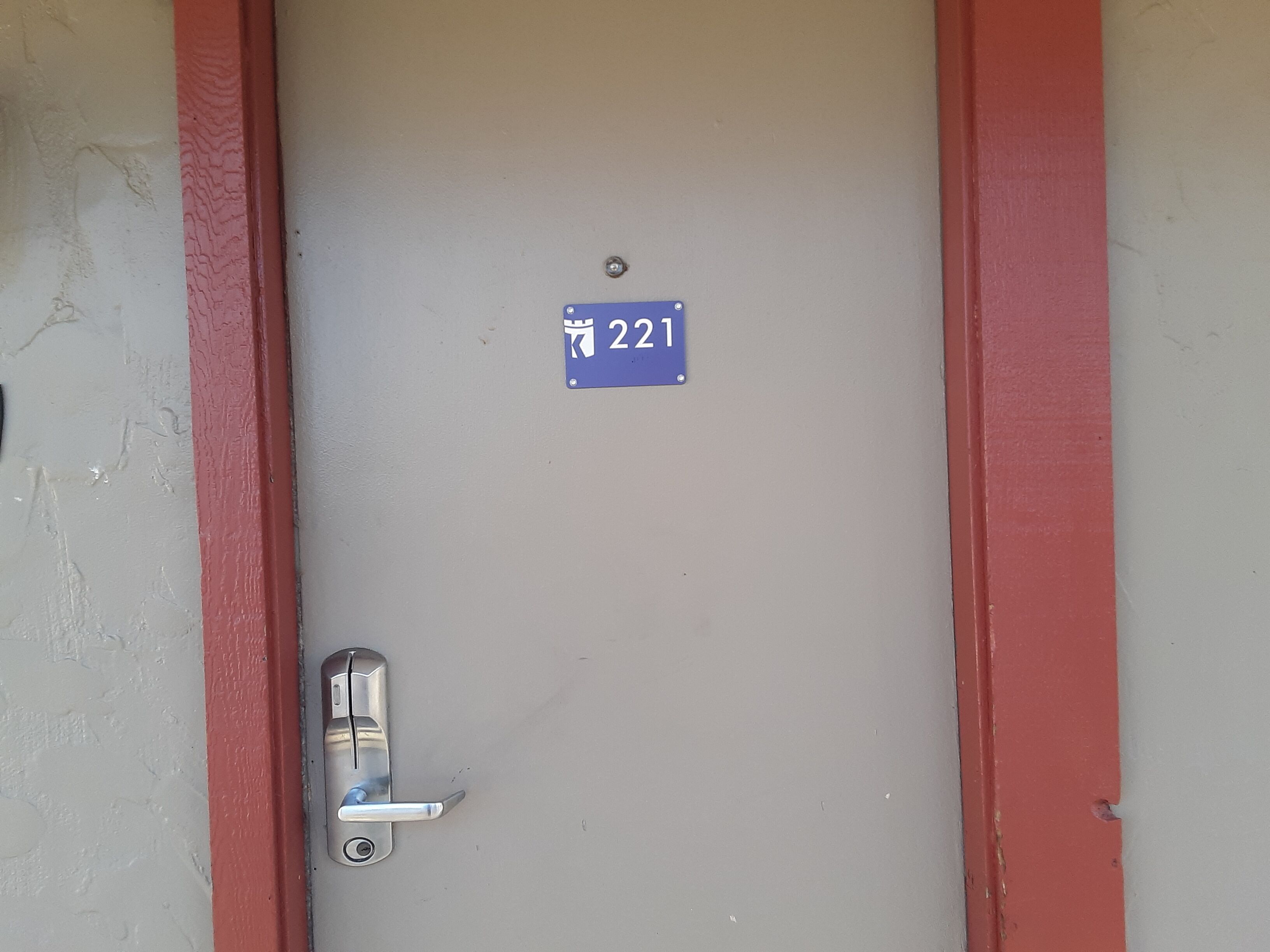 Una puerta con un letrero azul que indica el número de habitación 221.