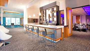 Un vestíbulo de hotel con una zona de bar, asientos y una sección de comedor.