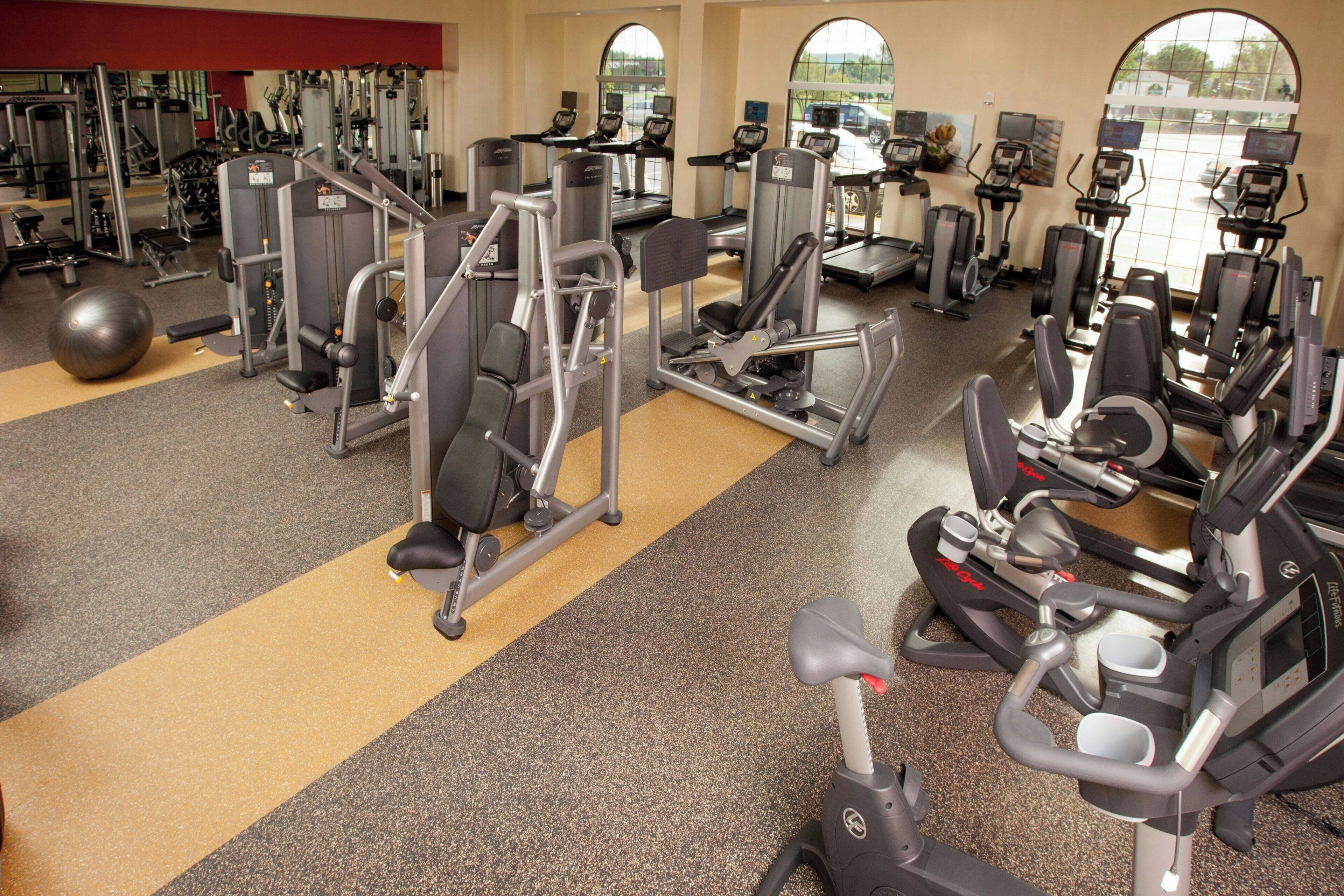 A gym with various exercise machines, a ball, and a yellow line on the floor.