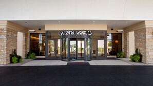 A hotel entrance with a revolving door, glass doors, and a brick facade. - Minneapolis Marriott Northwest Hotel & Conference Center (Brooklyn Park)