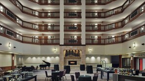 A multi-level hotel lobby with a piano, dining tables, and a bar area. - Minneapolis Marriott Northwest Hotel & Conference Center (Brooklyn Park)